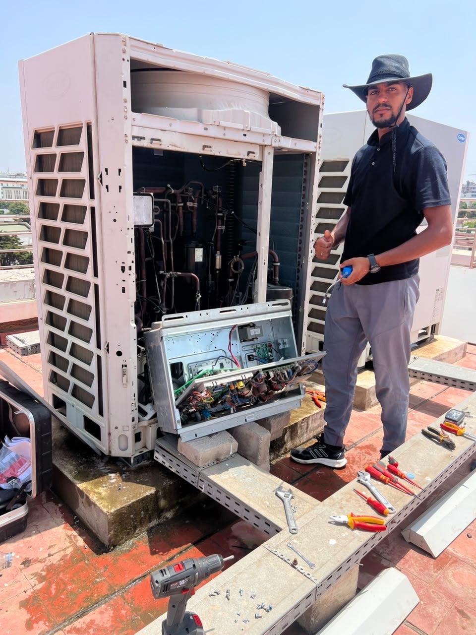 Technicien E.L.M devant un groupe de climatisation ouvert pour maintenance